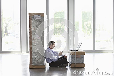 Wan With Cellphone And Laptop Between Packages At Empty Office