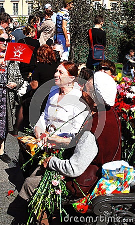 A war veteran woman receives flowers, she smiles.