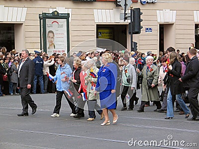 War veterans and young people walk with flowers on the Nevsky prospect.