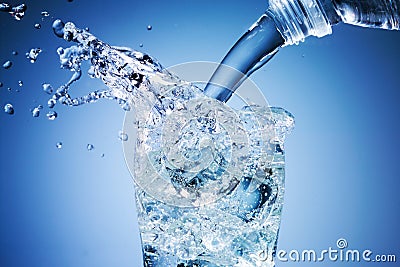 Water is pouring into glass on blue background