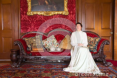 Wax lady sitting on red sofa