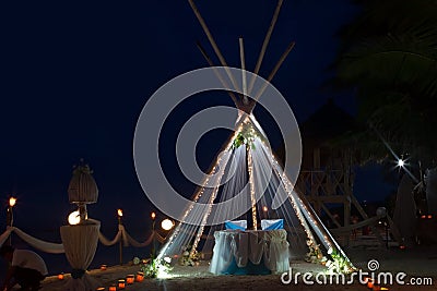 Wedding arch and set up with flowers on beach at night