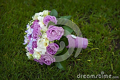 Wedding bouquet of purple and white roses lying on grass