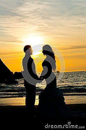 Wedding couple silhouette on the beach holding hands.