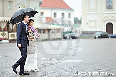 Wedding couple waking by the rain