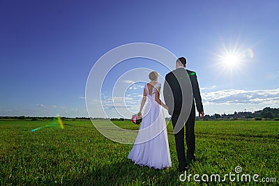 Wedding couple walking through green field