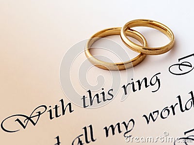 Two wedding rings on a paper with text of wedding vow.
