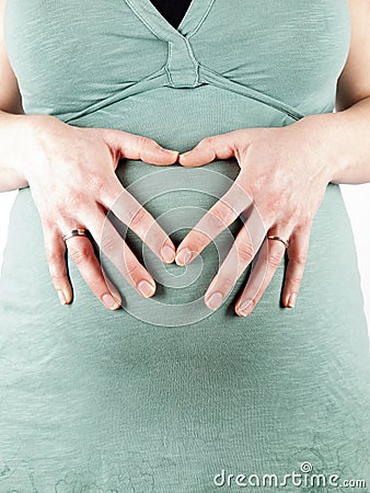 36 weeks pregnant young woman making a heart over her belly