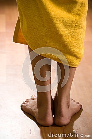 Wet female legs with towel on wooden floor