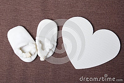 White baby shoes and plastic heart over brown