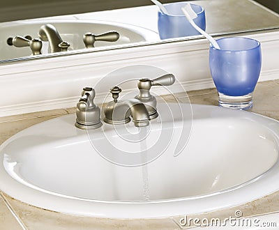 White Bathroom Sink and Faucet in Open Position with Clean Water