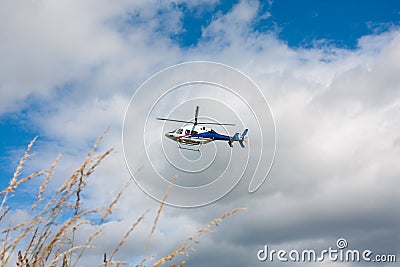 White blue red painted helicopter in flight