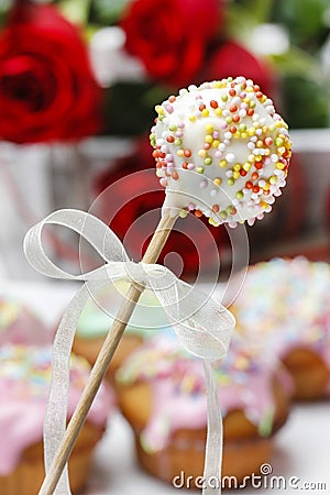 White cake pops. Colorful muffins in the background