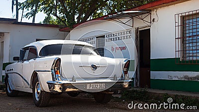 A white classic car parked front of house