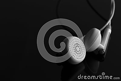 White earphones on reflective black