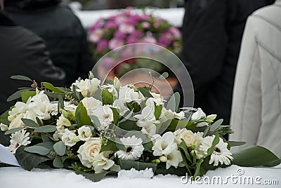 White Funeral flowers in the snow before a caket