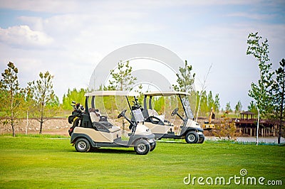 White golf car on the green golf field on beautiful sunny day