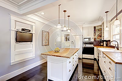 White kitchen with wooden counter top island and TV
