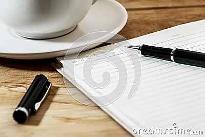 White notebook, pen and cup of coffee