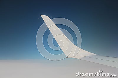 White wing of a plane over blue sky