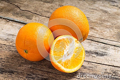 Whole and Cut in Half Orange lying on Weathered Wooden Table
