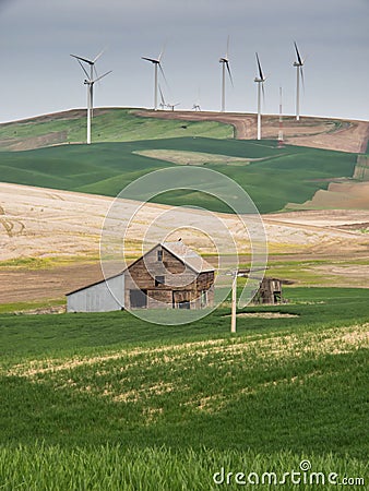 Wind turbines on the hill tops with wheat fields and barn