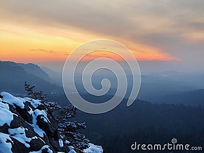 Winter daybreak in sandstone rocks of Bohemian-Saxon Switzerland park. View from the rock peak over valley.