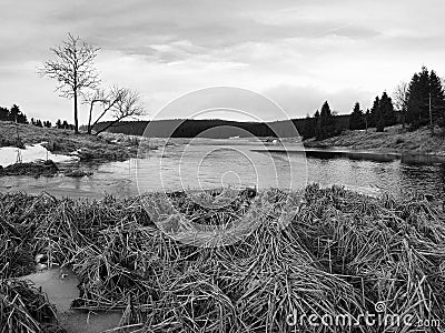 Winter view over lake with thin blue ice to opposite bank