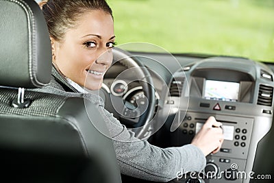 Woman adjusting radio volume in the car