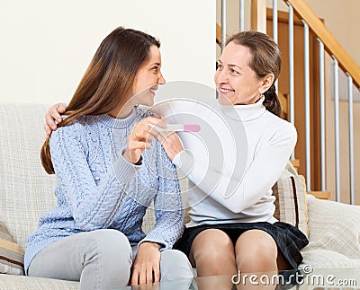 Woman and adult daughter rejoicing pregnancy test