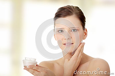 Woman applying moisturizer cream on face