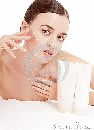 Woman applying moisturizer cream on face.