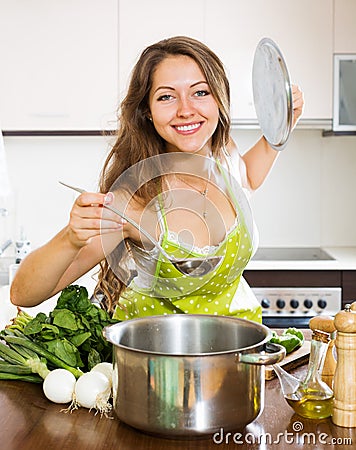 Woman in apron cooking soup in kitchen