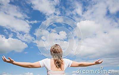 Woman with arms outstretched against blue sky and clouds