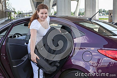 Woman with baby safety seat placing it in the car