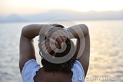 Woman with back seahorse tattoo standing alone looking at sea horizon