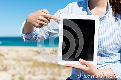 Woman by the beach pointing on tablet-pc