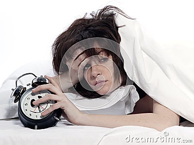 Woman in bed awakening tired holding alarm clock