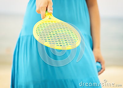 Woman in blue dress playing tennis on the beach