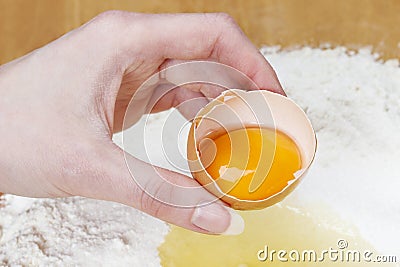 Woman breaking eggs into four to make bread dough