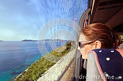 Woman in the bus looks out of the window on a sea landscape