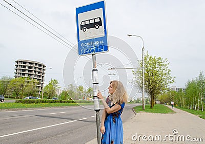 Woman at bus stop with pole tags driving schedules