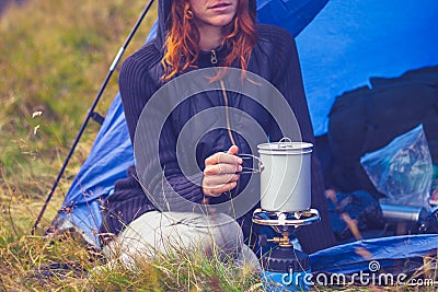 Woman camping and cooking with portable stove