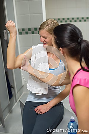 Woman checking friend s muscles at changing room