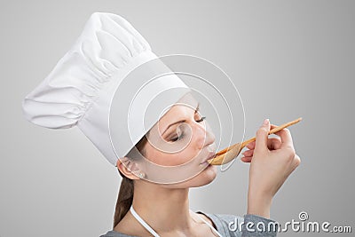 Woman in chef s hat tasting sauce