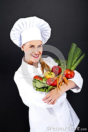 Woman chef with vegetables on her hands over dark background