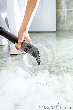 Woman cleaning drain in bathroom with steam