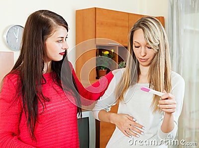 Woman consoling the depressed girl with pregnancy test