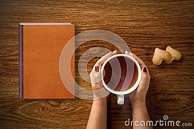 Woman with cup of tea, cookies and book on wood