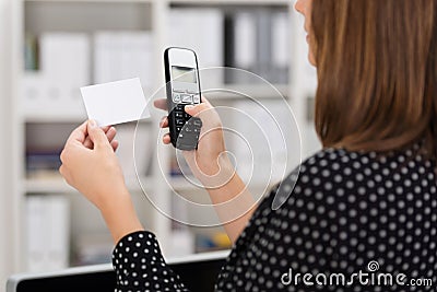 Woman dialing a number on a business card